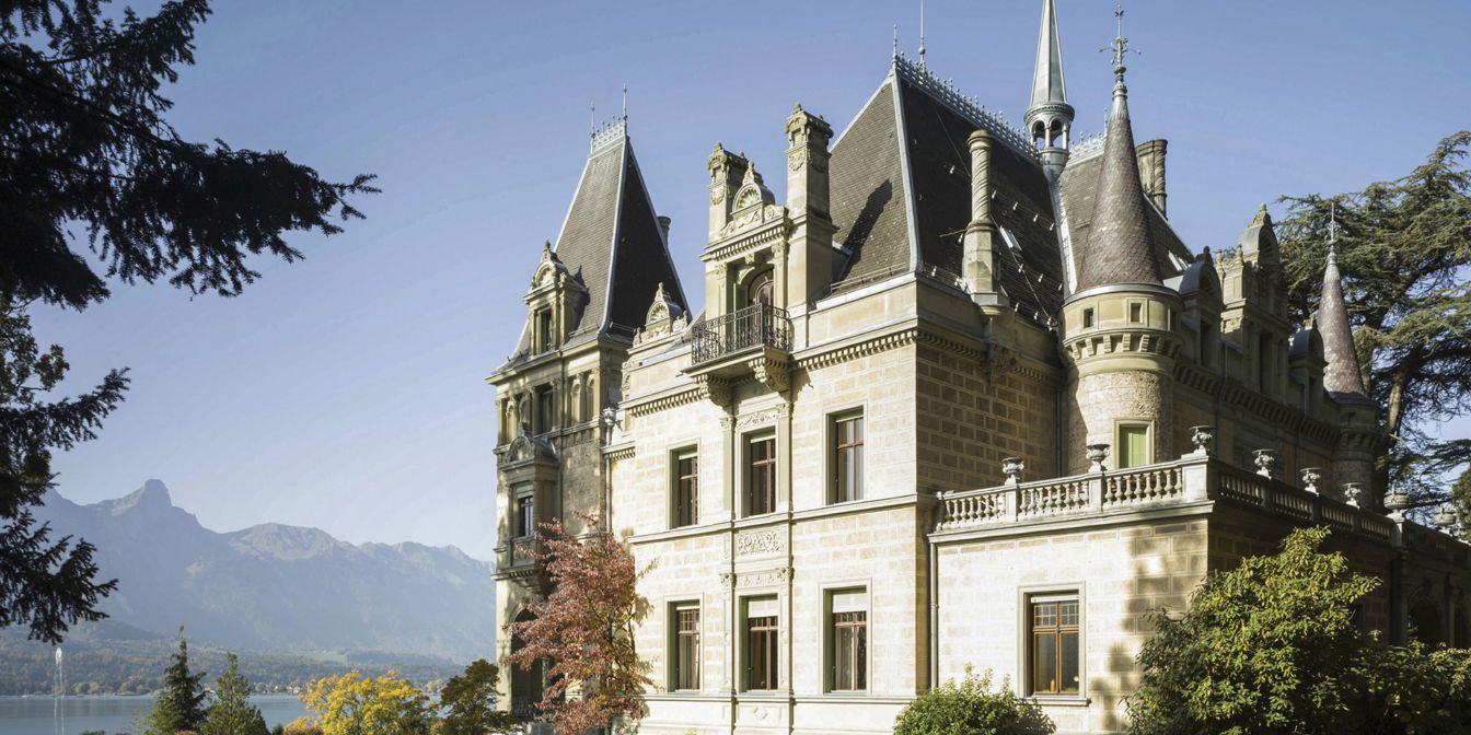 Majestätisches Schloss Hünegg am Ufer des Thunersees, umgeben von gepflegtem Garten und atemberaubender Bergkulisse. Die historische Fassade und die idyllische Lage schaffen den idealen Rahmen für exklusive Firmenevents, Seminare oder Tagungen in der Schweiz. © Schloss Hünegg Schloss Hünegg Panoramaansicht