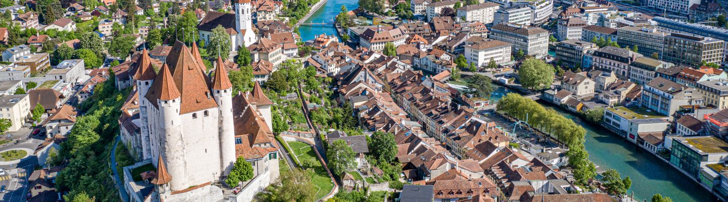 Luftaufnahme von Thun mit Schloss und Alpenpanorama