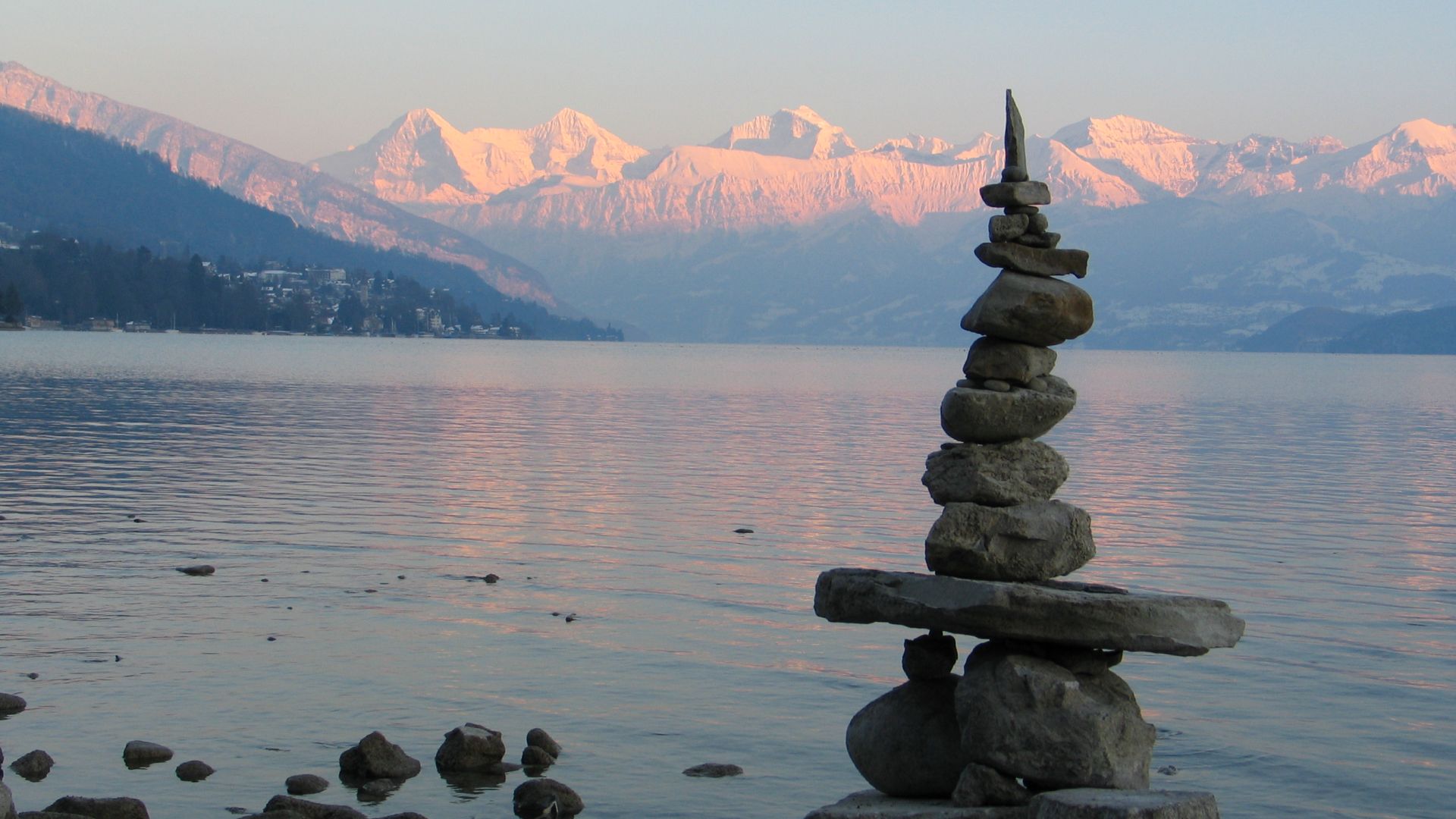 Steinmännchen am Ufer des Thunersees mit Alpenpanorama in der Dämmerung