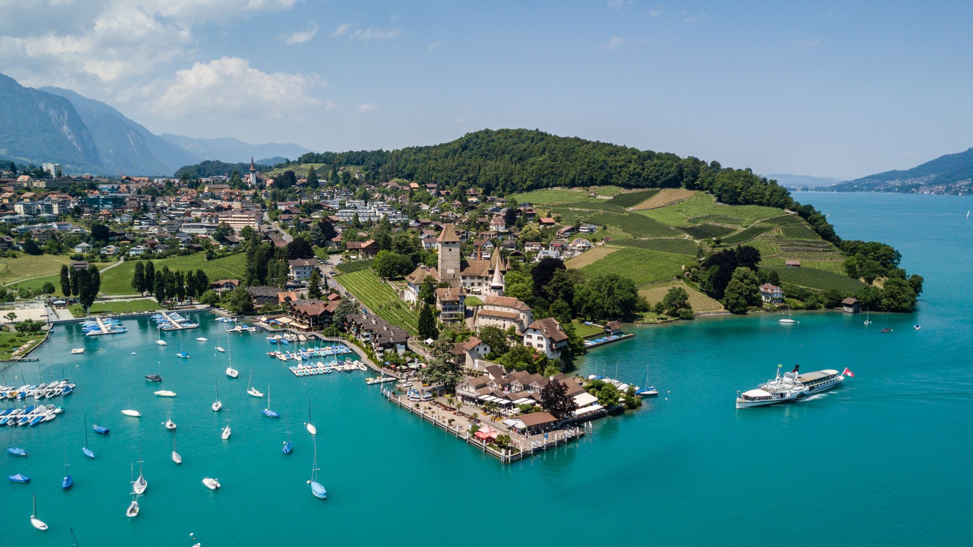 Luftaufnahme von Spiez am Thunersee mit Hafen, Segelbooten und Schloss