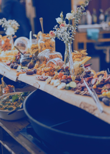 Liebevoll angerichtetes Catering mit Käse, Früchten und Snacks – ideal für Business-Events in der Region Thun-Thunersee.
©Frachtraum Thun Apéro-Riche-Buffet auf Holzbrett mit Fingerfood und Blumen dekoriert