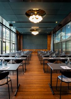 Heller Konferenzraum in Reihenbestuhlung mit Holzboden, moderner Beleuchtung und Blick ins Grüne – ideal für Meetings und Workshops in der Region Thun. ©Hotel Aare Moderner Seminarraum mit Tischreihen und Panoramafenstern am Thunersee