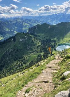 Bergwanderweg mit Stufen und Panoramablick auf Gipfel und Bergsee bei Thunersee