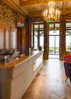 Exklusiver Empfangsbereich in einem historischen Gebäude am Thunersee. Edle Holzvertäfelung, luxuriöse Sitzgelegenheiten und große Fenster schaffen ein stilvolles Ambiente mit direktem Blick auf den See – ideal für Networking-Events, Geschäftsanlässe und stilvolle Meetings mit inspirierendem Ausblick. ©Schloss Schadau Eleganter Empfangsbereich mit Seeblick