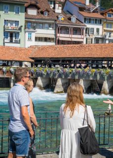 A guide explains the Aare River and the weir to a group; in the background, the lower lock and historic façades in Thun. ©mikekaufmann Guided tour of the Aare weir in Thun with a view of the lower lock