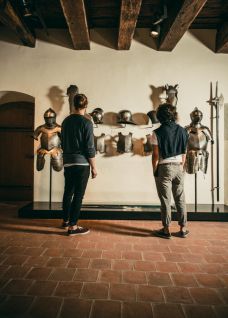 Zwei Personen betrachten Ritterr&uuml;stungen in historischer Ausstellung in Spiez