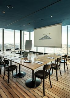 Bright meeting room with floor-to-ceiling windows, wooden terrace and central conference table for workshops and meetings. A screen and flipchart support professional presentations, while the sweeping views of the city and countryside create an inspiring atmosphere for business events on Lake Thun. Seminar room with panoramic view