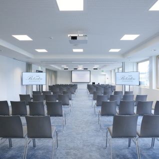 Bright seminar room with theatre-style seating and presentation screen in Thun