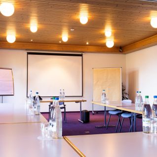 Heller Seminarraum mit U-Form-Bestuhlung und Präsentationsleinwand in der Thunersee-Region