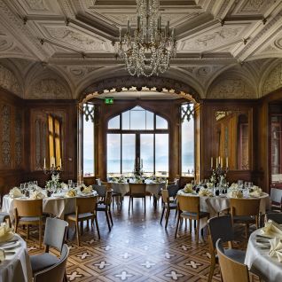 Eleganter Bankettsaal mit gedeckten Tischen und Seeblick in der Thun-Thunersee Region