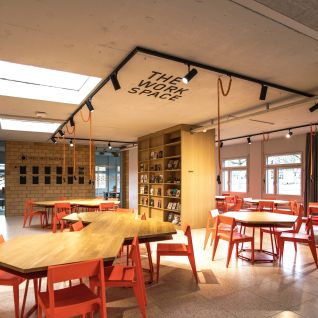 Moderner Meetingraum „The Workshop Space“ mit Tischen und roten Stühlen in Thun