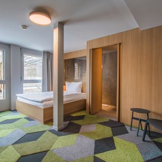 Modernes Hotelzimmer mit Doppelbett, Holzverkleidung und gemustertem Teppich