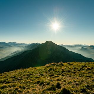 Sunrise over the Alpine panorama by Lake Thun, with a green mountain meadow in the foreground