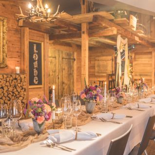 Festlich gedeckte lange Tafel in rustikalem Chalet für Business-Event am Thunersee