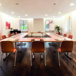 Heller Seminarraum mit U-Bestuhlung, Parkettboden und Tageslicht