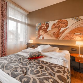 Modernes Doppelzimmer mit Kunstkopfteil, Doppelbett und Fenster mit Vorhängen