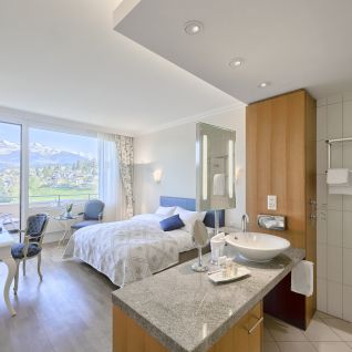 Modernes Hotelzimmer mit Doppelbett, Schreibtisch und Bergblick am Thunersee