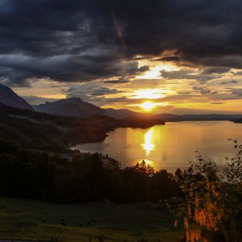 Sonnenuntergang über dem Thunersee mit Alpenpanorama und dramatischen Wolken