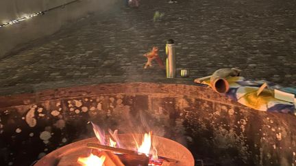 A fire pit in the evening with fairy lights in the background