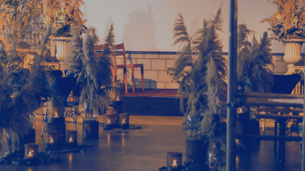 Stimmungsvolle Setup-Szene für Business-Events: Kerzen, Lampions und Trockenblumen arrangiert entlang eines Gangs in eleganter Location. ©Frachtraum Thun Stilvolle Event-Location mit Kerzenlicht und Trockenblumen-Dekor in warmem Abendlicht