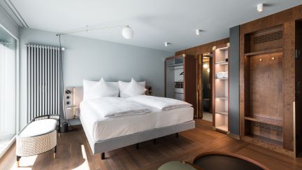 A modern double room with a box-spring bed and wooden features at the Thunersee Hotel