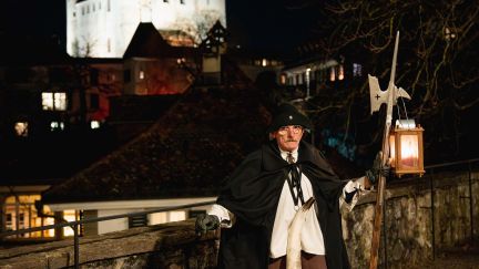 A night watchman in historical costume outside Thun Castle at night