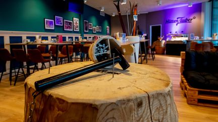 Stilvoller Indoor-Eventraum mit grossem Holztisch, Barbereich und Sitzgruppen – ideal für Meetings, Apéros und Firmenanlässe in der Region Thun-Thunersee. ©Stockhorn Arena Eventraum mit Holztisch, Bar und Lounge-Bereich in Thun-Thunersee