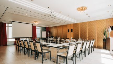Modern meeting room in Thun-Thunersee: U-shaped layout, natural light, screen and elegant ambience – ideal for workshops and conferences. ©Hotel Krone A bright seminar room with U-shaped seating and a projection screen