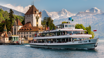 Auf dem Thunersee fährt das Ausflugsschiff „MS Stadt Thun“ vor dem Schloss Oberhofen, eingerahmt von Alpenpanorama und blauem Himmel. Die Szene vermittelt Schweizer Eventflair am Wasser – ideal für Firmenanlässe, Meetings oder Incentives in der Region Thunersee. ©Schloss Oberhofen Schloss Oberhofen & MS Stadt Thun