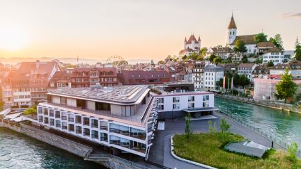 Moderne Eventlocation in Thun direkt an der Aare, mit Terrassen und Aussicht auf die Altstadt – ideal für Meetings, Kongresse und Firmenanlässe. ©Hotel Aare Kongresszentrum Thun am Aareufer mit Blick auf Altstadt und Schlosskirche