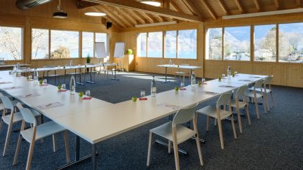 A bright seminar room with U-shaped seating and views of the mountains by Lake Thun