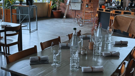 A set event table in a stylish industrial venue with a bar and tall windows in Thun