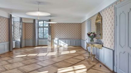 An elegant, light-filled room with herringbone parquet flooring, period features and a mirrored console table – a stylish venue for meetings in the Lake Thun area. A bright lounge with parquet flooring, stucco and large windows, ideal for business events