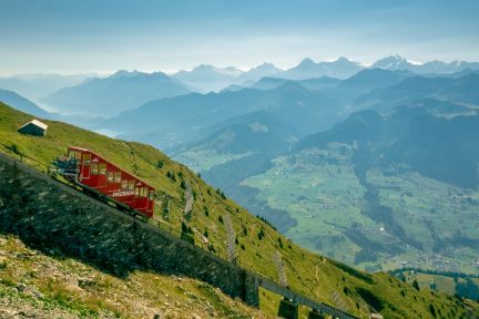 The Niesenbahn railway on the steep mountainside; in the background, vast Alpine valleys and peaks – an inspiring backdrop for incentives and meetings in the Lake Thun region. @Niesen A funicular railway on a hillside offering sweeping views of the Swiss Alps near Thun