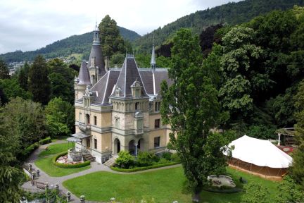 Blick auf Schloss Schadau in Thun: historisches Venue am Thunersee, umgeben von Park und Bergen – mit weissem Zelt für Veranstaltungen. ©Schloss Hünegg Schloss Hünegg am Thunersee mit Parkanlage und Eventzelt im Grünen