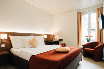 Helles Einzelzimmer mit Schreibtisch, Sessel und gro&szlig;em Fenster