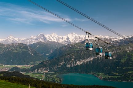 Mehrere Gondeln schweben über dem Tal; im Hintergrund glitzern Thunersee und schneebedeckte Gipfel – inspirierende Kulisse für Events in der Region Thun. ©Niederhorn Seilbahn-Gondeln mit Blick auf den Thunersee und die Berner Alpen