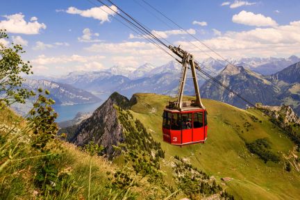 Rote Seilbahn-Gondel &uuml;ber gr&uuml;nen Bergh&auml;ngen mit Blick auf den Thunersee