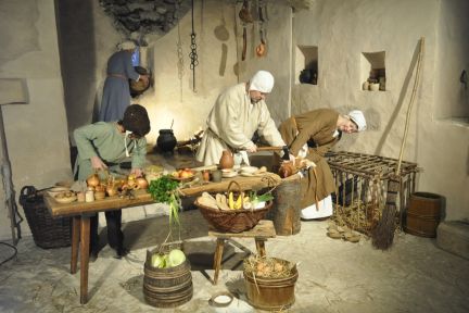 Authentische Museums-Szene mit Kochstelle, Körben und Zutaten – stimmungsvolles Rahmenprogramm für Events in der Region Thun–Thunersee. ©Schloss Spiez Historische Küche im Schloss: Mitarbeitende bereiten Speisen am Arbeitstisch zu