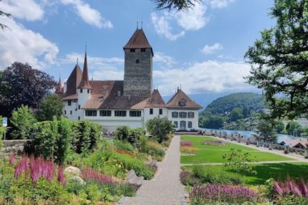 Sommerlicher Schlosspark mit Blumenbeeten und Kiesweg zum Schloss Schadau; rechts glitzert der Thunersee – ideale Kulisse für Business-Events. ©Schloss Spiez Schloss Schadau in Thun mit Blick auf den Thunersee und die Alpen