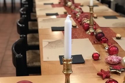 Stimmungsvolle, längliche Festtafel mit goldenen Kerzenhaltern, roten und goldenen Weihnachtskugeln sowie edlen Platzdeckchen. Perfekt für Firmenfeiern, Meetings oder festliche Anlässe rund um den Thunersee. Die festliche Dekoration schafft eine einladende Atmosphäre für erfolgreiche Geschäftsveranstaltungen. © Schloss Hünegg Festlich gedeckte Tafel für Geschäftsevents