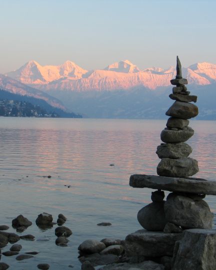 Steinm&auml;nnchen am Ufer des Thunersees mit Alpenpanorama in der D&auml;mmerung