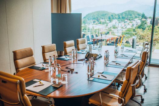 Heller Seminarraum mit runder Tafel, Wasserflaschen und Notizblöcken – inspirierendes Setting für Business-Meetings am Thunersee. ©Eden Spiez Moderner Meetingraum mit grossem Konferenztisch und Blick auf den Thunersee
