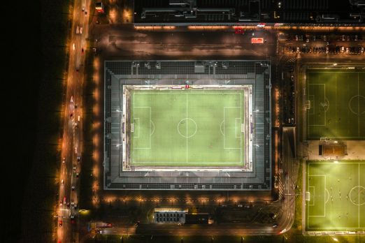 Luftaufnahme eines beleuchteten Fussballstadions bei Nacht in Thun