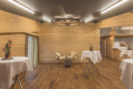 Warmer, moderner Raum für Apéros und Meetings mit Holzwänden, Stehtischen und Barbereich – ideal für Business-Events in der Thunerseeregion. ©Loube Spiez Rustikaler Eventraum mit Holzverkleidung und Stehtischen