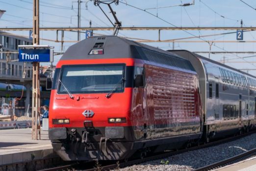 Ein moderner roter Intercity-Zug fährt in den Bahnhof Thun ein. Die markante Beschilderung und die Gleisinfrastruktur zeigen Wege zur optimalen Anreise für Meetings und Events in der Region Thunersee. Ideal für Geschäftskunden und Veranstaltungsplaner. ©SBB Ankunft am Bahnhof Thun