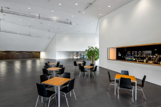 Grosszügige, moderne Lobby mit Bar, Hochtischen und Sitzbereichen – ideal für Apéros, Networking und Pausen bei Meetings im Thunerseegebiet. ©KKThun Helle Eventlobby mit Bar und Lounge-Sitzgruppen für Business-Events in Thun