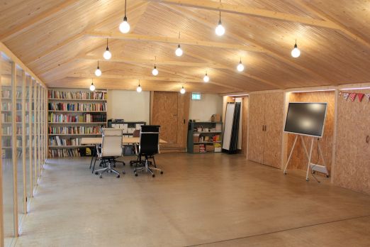 Heller Seminarraum mit Holzdecke, Bibliothek und Bildschirm in der Thunersee-Region