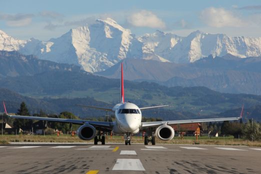 Helvetic Airways auf Startbahn vor Alpenpanorama