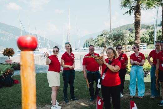 Team in roten Poloshirts am Thunersee-Ufer bei Outdoor-Event mit Segelbooten